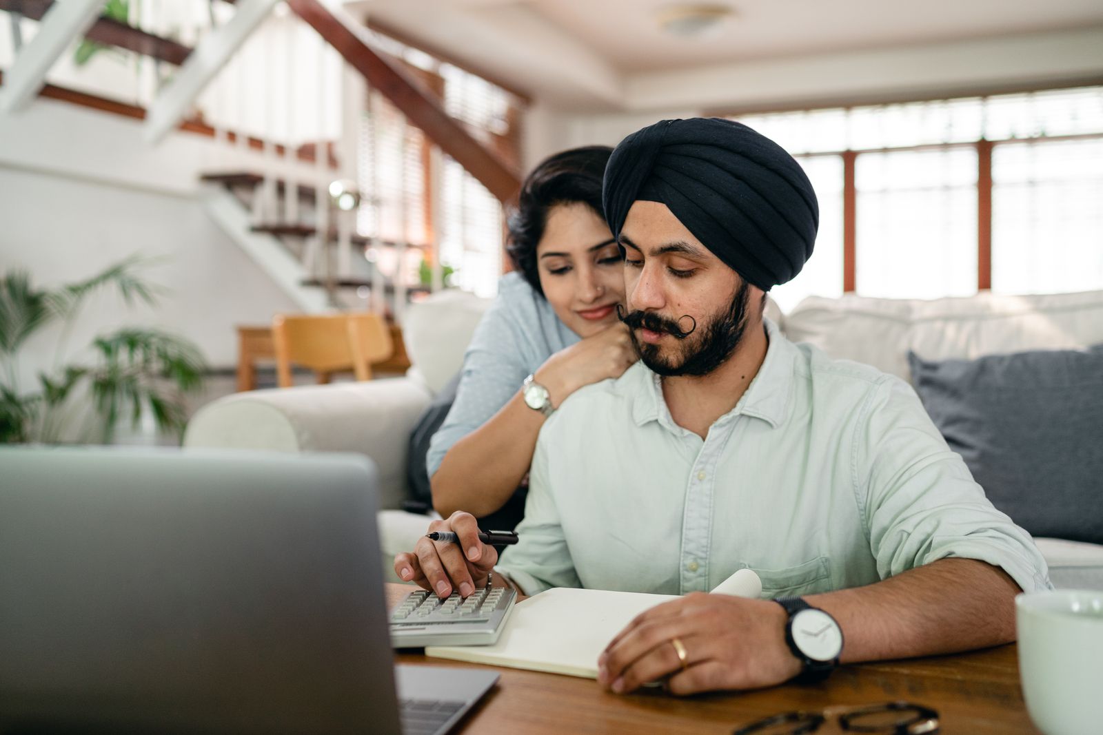 Indian couple at a table reviewing bills with a calculator — planning family healthcare spend